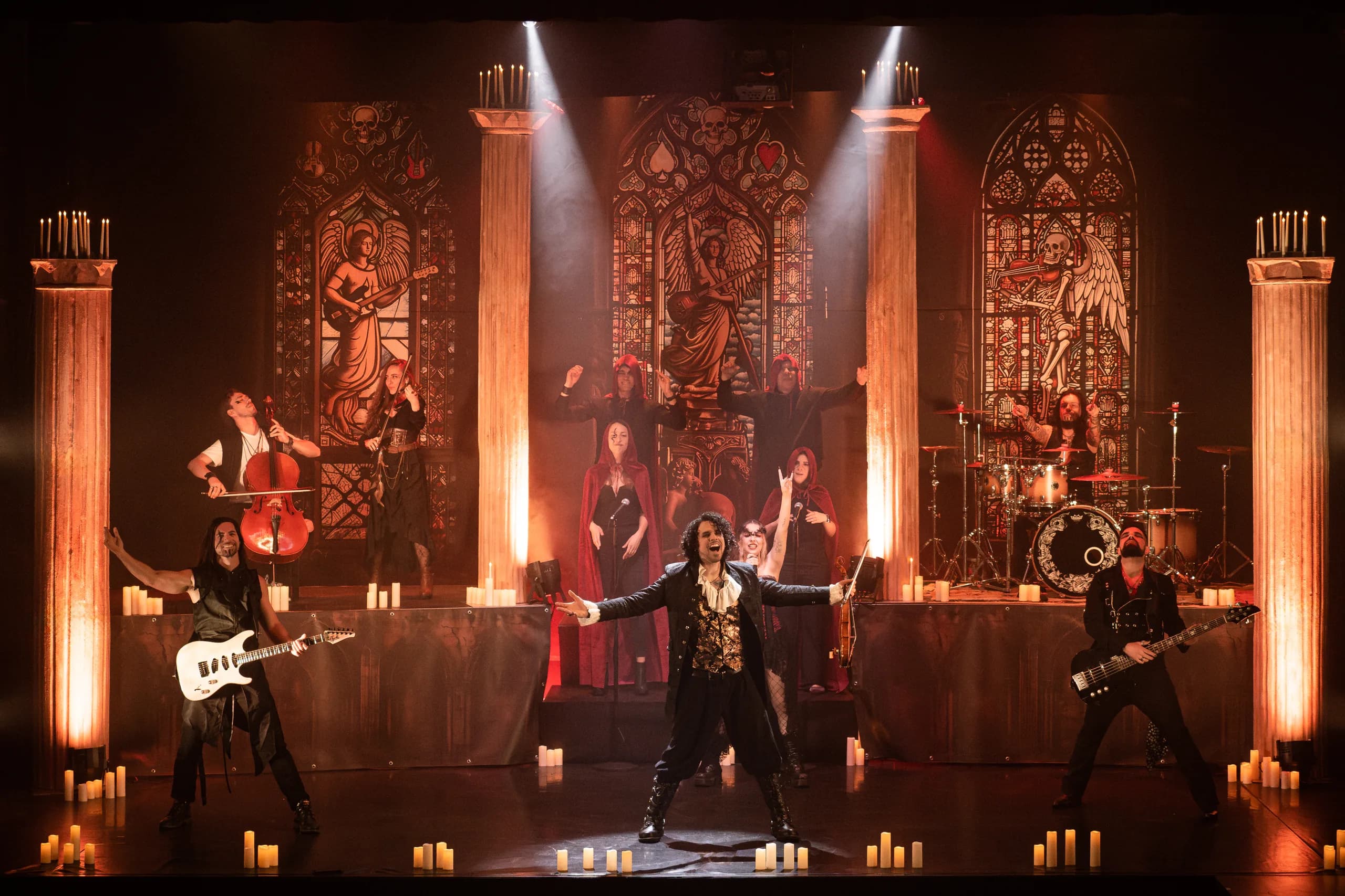 La banda de Rock Adagio en concierto: escenario con vidrieras góticas y velas; figura central con los brazos abiertos entre guitarristas y cuerda.
